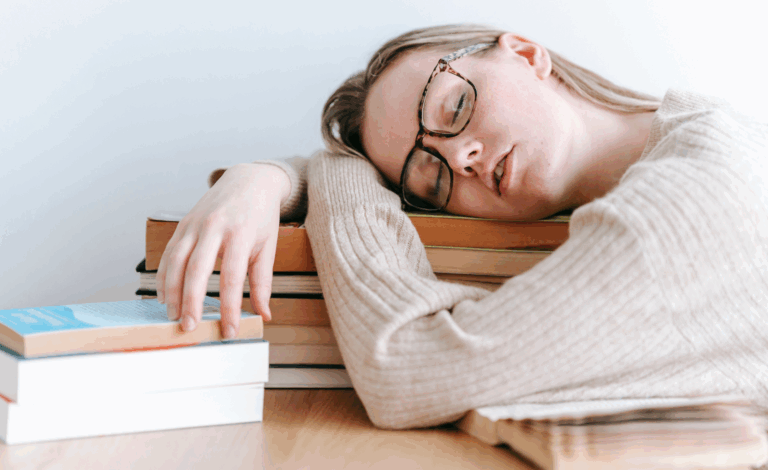 Woman sleeping on stack of books.